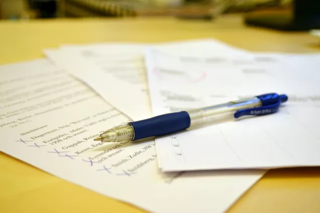 Blue pen on top of three pieces of paper on a table. Photo by Louise Larsson.
