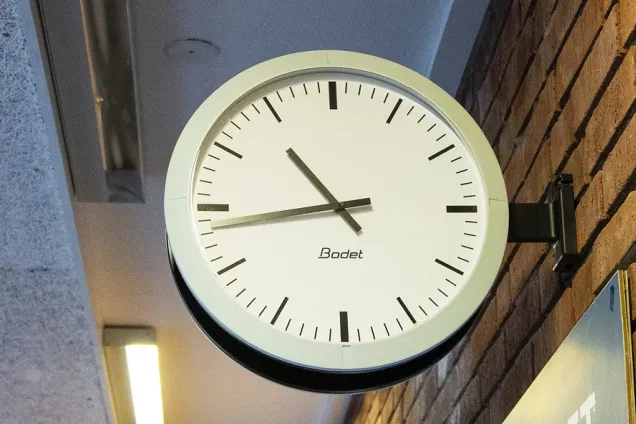 A white clock with black indicators attached to a brick wall by the right side (picture by Charlotte Carlberg Bärg)