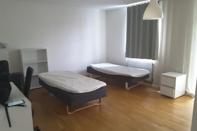 An overview of twin studio flat 1207 at housing area Malmö Folkets Park showing two beds in the middle of the room with a desk and as small bookcase to the left (picture)