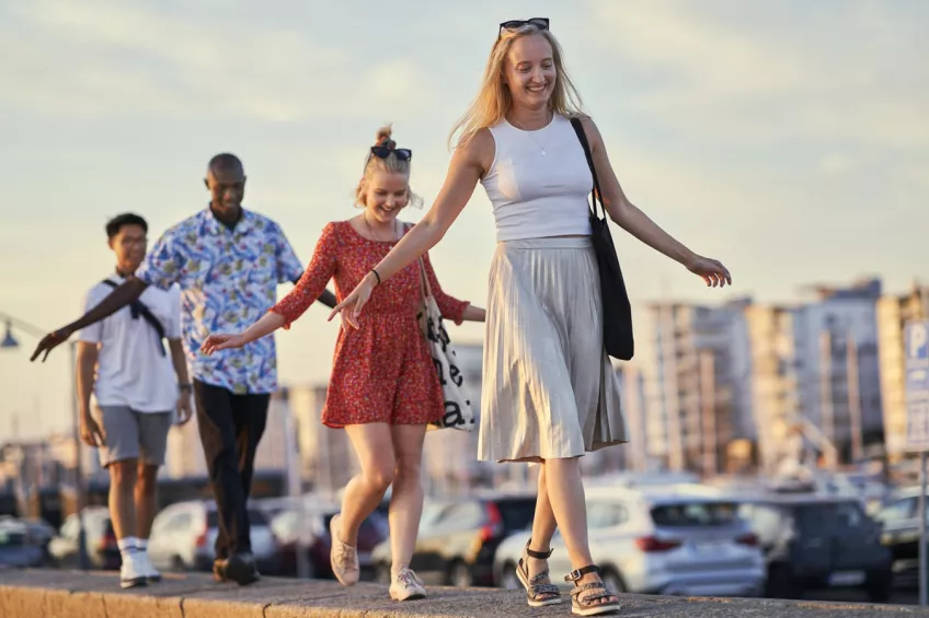 Four students balancing in a row holding out their arms. In the background cars and houses are visible out of focus. Picture by Johan Persson.