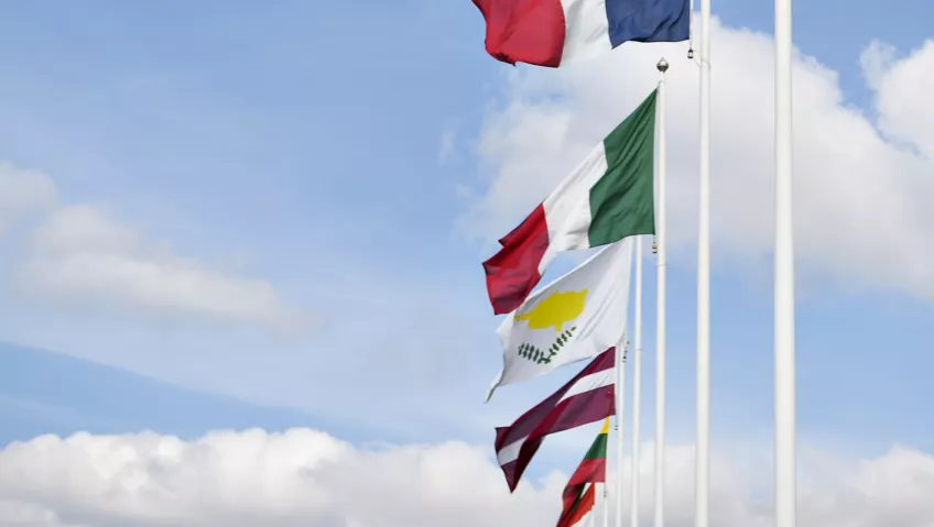 Several flags on poles with a blue and clowdy sky behind them (photo by Johan Persson)