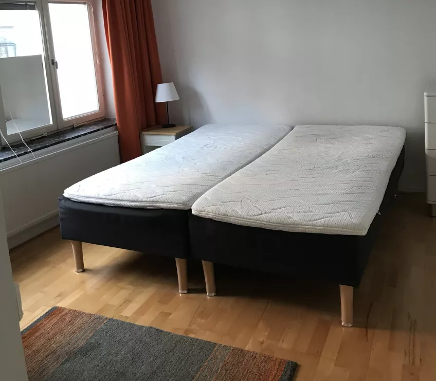 An overview of the bedroom at the housing area Kyrkogatan showing the two beds in the middle and the window to the left (picture)