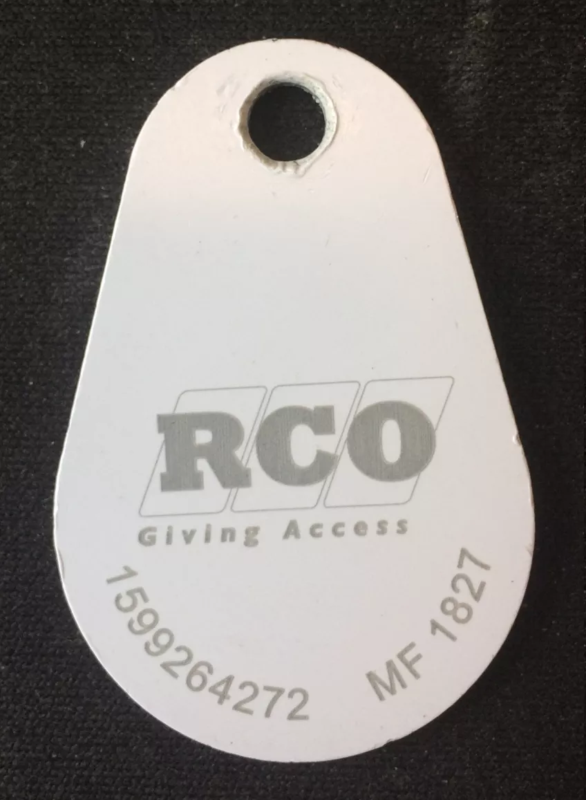 A white tag against a black background with the text RCO in grey printed on it. (picture)