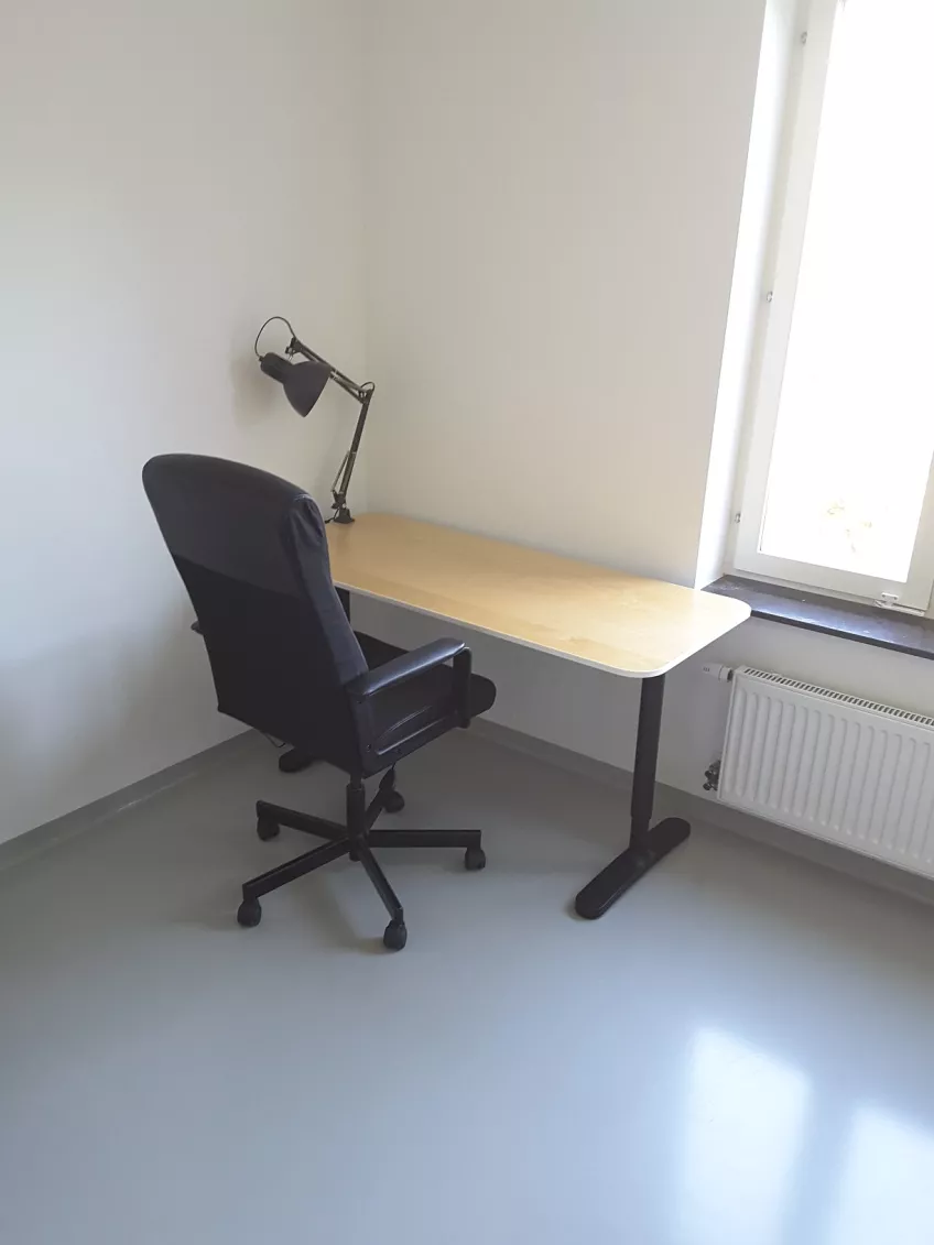An overview of the study area in private bedroom 1308B at housing area Sofieberg showing a desk chair, desk and desk lamp (picture)