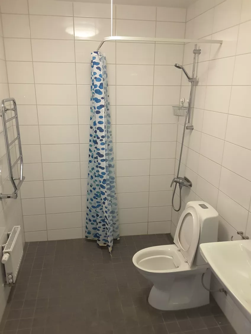 Overview of shared bathroom in apartment 1408 at housing area Sofieberg showing the sink, toilet and shower to the right and shower curtain in the middle (picture)