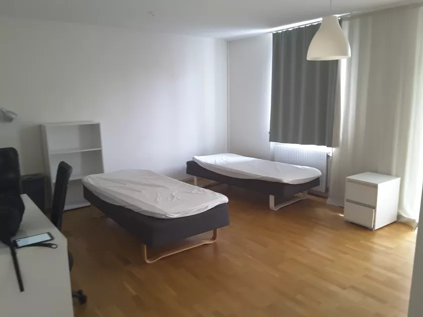 An overview of twin studio flat 1207 at housing area Malmö Folkets Park showing two beds in the middle of the room with a desk and as small bookcase to the left (picture)