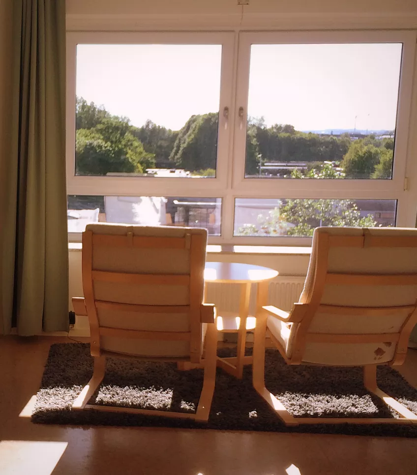 A picture inside an apartment at Klostergården Student House showing two armchairs and a coffee table on a rug facing a window (photo).