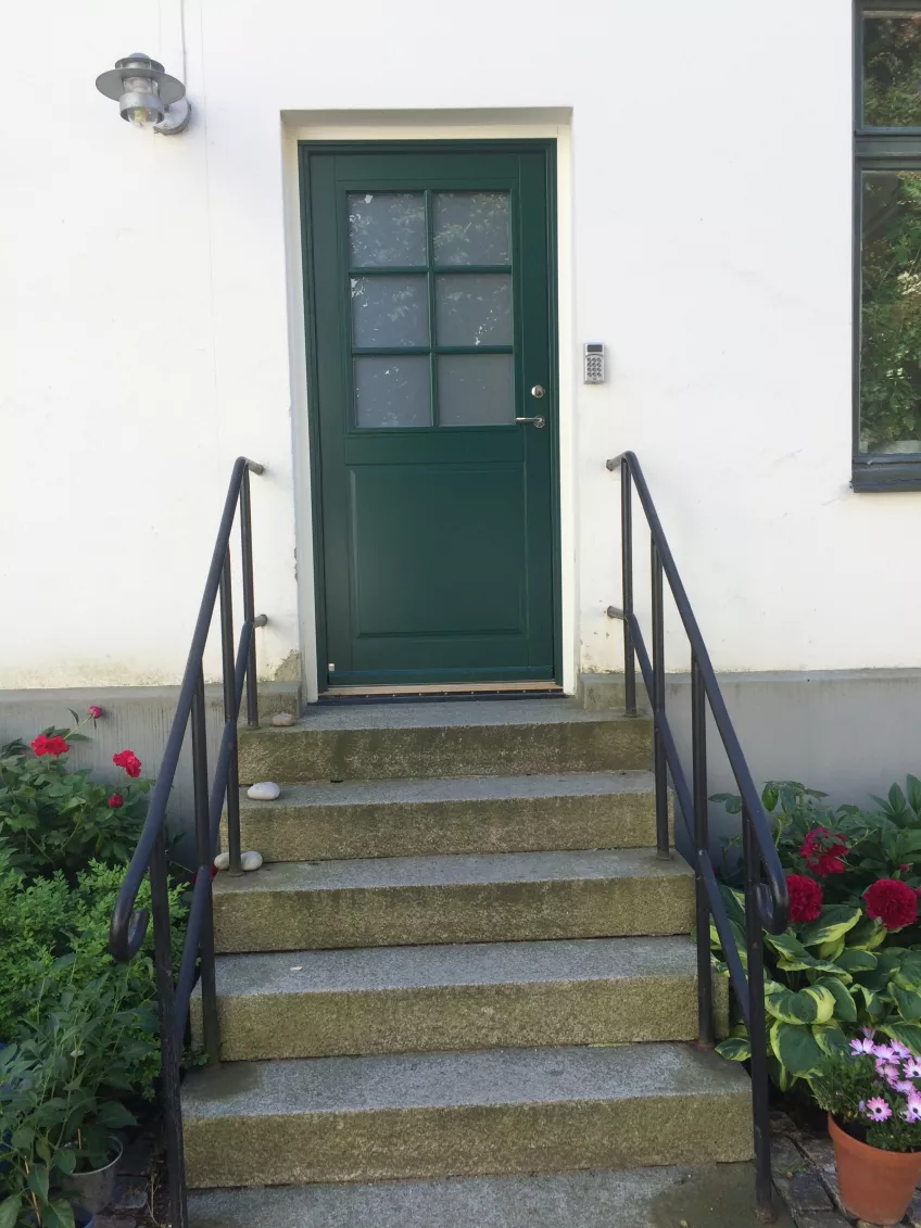 The courtyard entrance to the apartment at Kyrkogatan 15, a green door with a set of stairs leading up to it (photo).