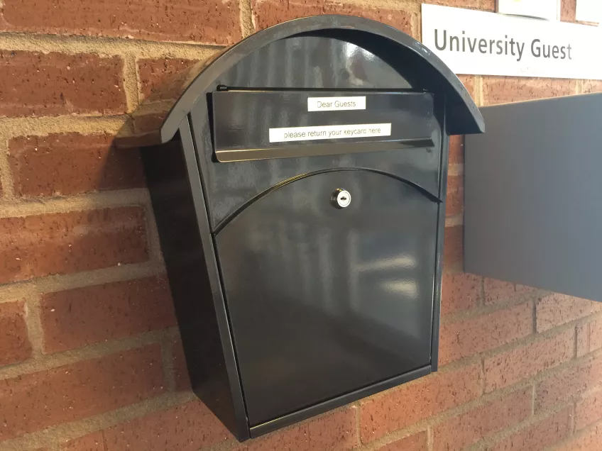 A black letterbox on a red brick wall, for returning keys. Photo by LU Accommodation.