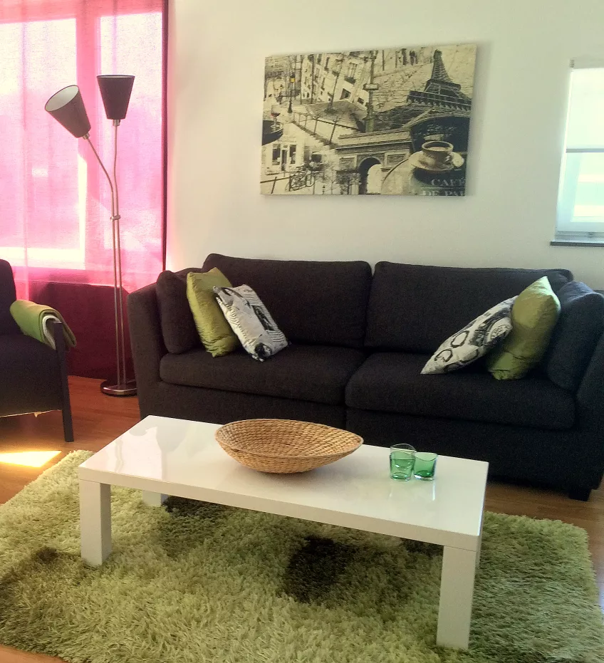 A picture of the living room at Orkestervägen 13B, showing a sofa, a coffee table, a rug, and a picture on the wall behind (photo).